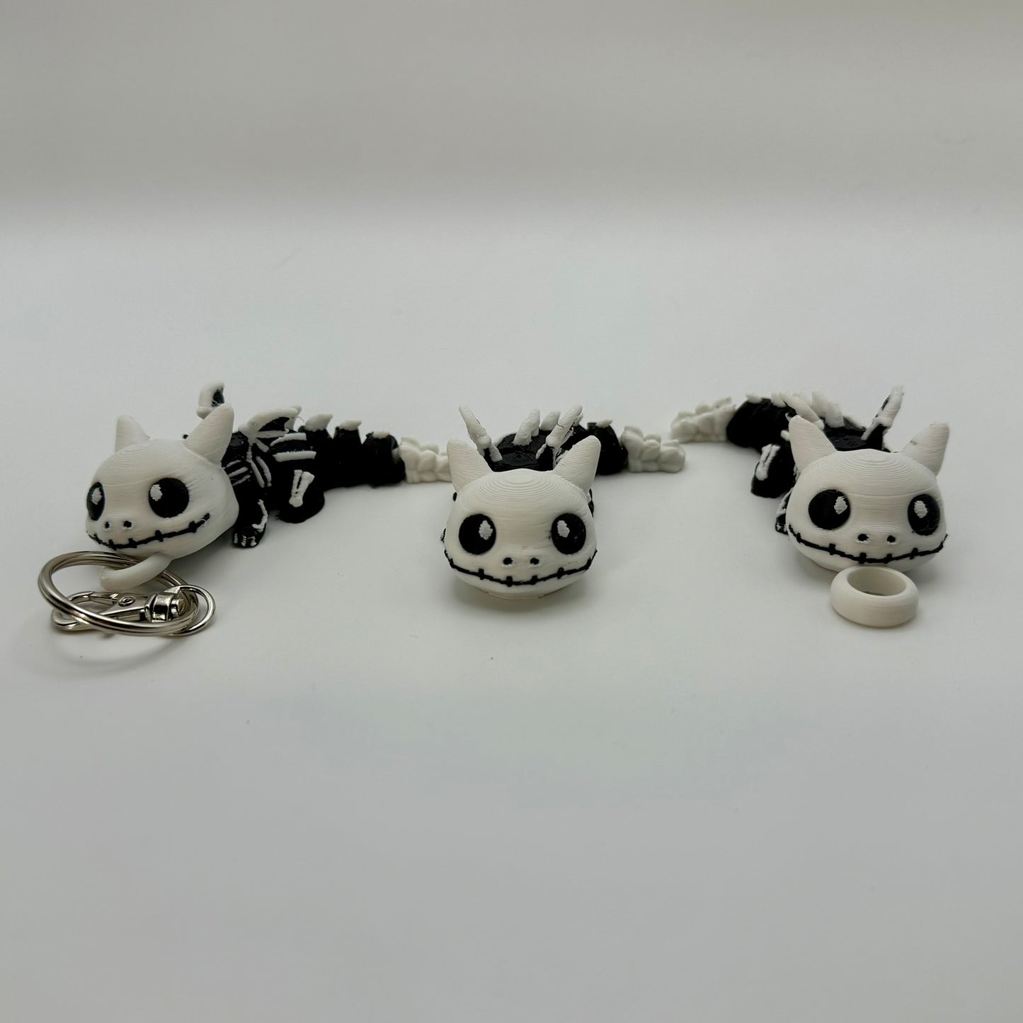Set of black and white dragon-shaped keychains on a light gray background